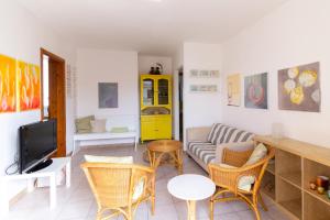 un soggiorno con divano, sedie e TV di Rainbow Apartment - Torre dell'orso a Torre dell'Orso