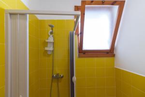 un bagno con doccia, piastrelle gialle e finestra di Rainbow Apartment - Torre dell'orso a Torre dell'Orso Altre 12 foto