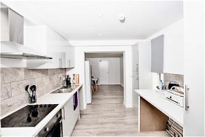 a kitchen with white counters and a long hallway at Dunamis Staycation 4 in Croydon