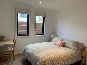 een slaapkamer met een bed en 2 ramen bij Affordable 2BR Apartment near Melbourne CBD in Maribyrnong