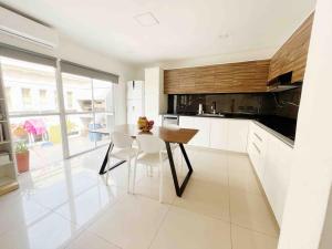 a white kitchen with a table and chairs in it at Hermoso depto centro Rosario in Rosario