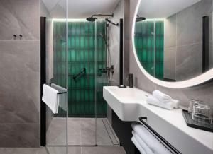 a bathroom with a sink and a shower with a mirror at Hyatt Place Krakow in Kraków