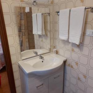 ein Badezimmer mit einem Waschbecken, einem Spiegel und Handtüchern in der Unterkunft Room Pappagnocca in Reggio nell'Emilia