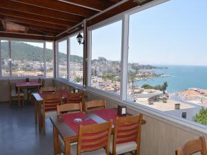 a restaurant with tables and chairs and a view of the ocean at Airport Güllük Otel in Milas