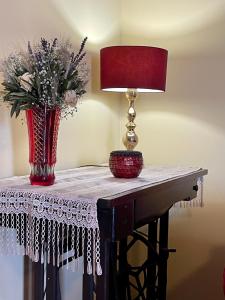 a table with a lamp and a vase of flowers on it at Lefkandi Family House in Chalkida