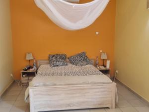 a bedroom with a bed with a white curtain above it at Magnifique Villa Riad avec piscine proche plage in Saly Portudal