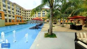 a pool at a hotel with a palm tree at 2BR Casa Mia Sanremo Oasis Cebu in Talisay