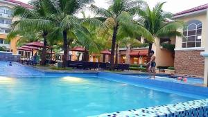 a man standing next to a swimming pool with palm trees at 2BR Casa Mia Sanremo Oasis Cebu in Talisay