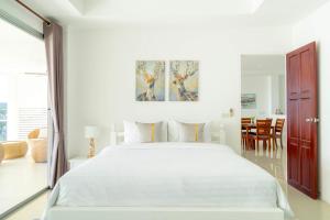a white bedroom with a large bed and a dining room at Kata Seaview Jacuzzi Suite - Pasifora in Kata Beach