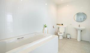 a white bathroom with a tub and a toilet at Kata Seaview Jacuzzi Suite - Pasifora in Kata Beach