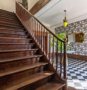 - un escalier en bois dans une maison avec un sol en damier dans l'établissement Château de Gouyas, à Montagrier