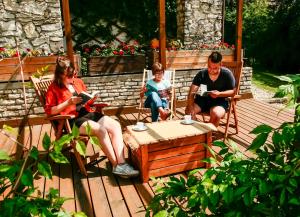 een man en een vrouw en een kind zittend in stoelen op een terras bij Podlesice 38 in Kroczyce