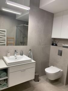 une salle de bain avec un lavabo blanc et des toilettes dans l'établissement Lake View Sea Apartment Rogowo Pearl, à Rogowo