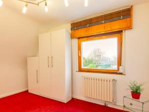 Zimmer mit einem Fenster, weißen Schränken und einem roten Boden in der Unterkunft Messewohnung Düsseldorf - Neuss in Neuss