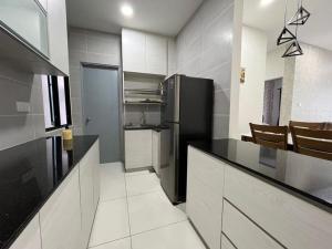 a kitchen with a black refrigerator and white cabinets at Homestay P residence 3 bedroom and 2 bathroom in Kuching