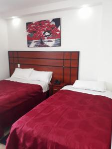 2 camas en una habitación de hotel con sábanas rojas en HOTEL DEL RIVER MONUMENTO en Sangolquí