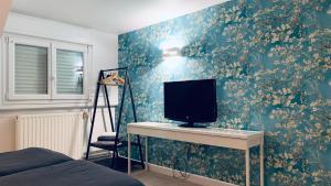 a bedroom with a tv on a wall with floral wallpaper at Greenfield Chambres d'Hôtes in Neufchâtel-Hardelot