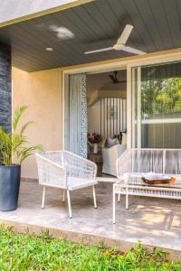 dos bancos blancos de mimbre sentados en un porche en Rainforest Woods, Assagao, Goa - Luxury 4 BHK Private Rooftop Pool en Assagao
