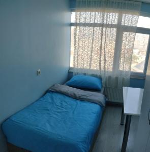 1 dormitorio con cama con sábanas azules y ventana en Golden Halich Hostel en Estambul