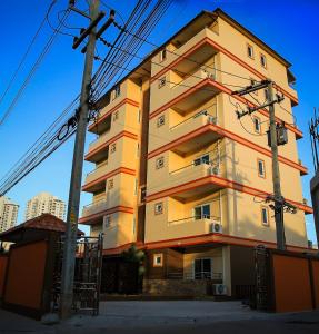 a tall yellow building with red stripes on it at Sky Villa Hua Hin Guesthouse - Adults-Only in Hua Hin