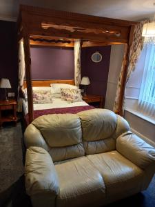 a bedroom with a bed and a leather couch at Virginia Cottage Guest House in Bowness-on-Windermere