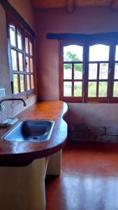 una cucina con lavandino e due finestre di MAMAICUNA CABAÑA a Tilcara