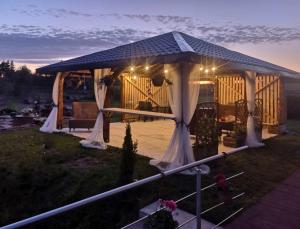 ein Pavillon mit weißen Vorhängen auf einem Feld in der Unterkunft Baltamiškio slėnis in Baltamiškis
