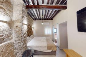 a bedroom with a bed and a stone wall at The house in the Ramchal in Acre