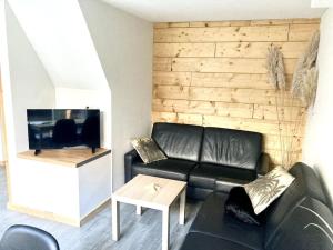 een woonkamer met een zwarte leren bank en een tv bij Cosy beach house for ocean & nature lovers in Noordwijk
