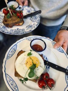 une personne détenant deux assiettes de nourriture avec des œufs et du pain grillé dans l'établissement Édouard Garden Café Guest Room, à Durbuy
