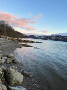 a body of water with rocks on the shore at Bell Rock Holiday Lodge in Killin