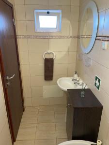 a bathroom with a sink and a toilet and a mirror at Alojamento Amor de Mãe in São Teotónio