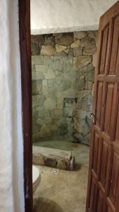 baño con pared de piedra y aseo en Casa Pachamama en Tilcara