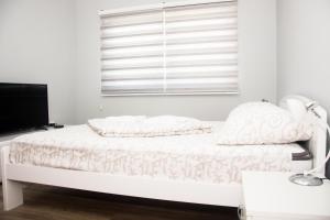 a white bedroom with a bed and a window at Motel Aura in Višegrad