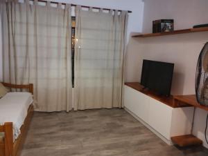 1 dormitorio con 1 cama y TV en un estante en Casa con pileta en Funes en Funes
