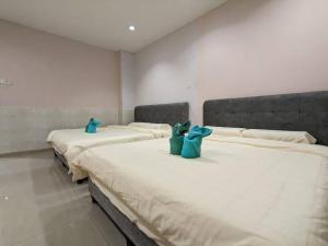 three beds in a room with blue bags on them at Cozy Spacious seremban Bangalow Taman Rasah in Seremban