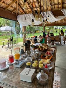 a buffet of food on a wooden table with people in the background at Aconchego da bocaina in Cunha