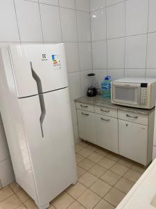 La cocina está equipada con nevera blanca y microondas. en Martin Quintanilha 1B, en Goiânia