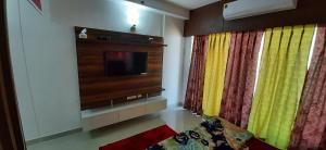 ein Wohnzimmer mit einem Flachbild-TV und Vorhängen in der Unterkunft Short Stays in Fully Furnished Service Apartment in Noida
