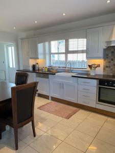 a kitchen with white cabinets and a table and chairs at Home On The Edge Of Ireland! in Belmullet