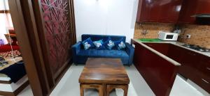 ein Wohnzimmer mit einem blauen Sofa und einem Tisch in der Unterkunft Short Stays in Fully Furnished Service Apartment in Noida