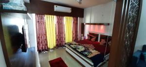 ein kleines Schlafzimmer mit einem roten Bett und Vorhängen in der Unterkunft Short Stays in Fully Furnished Service Apartment in Noida
