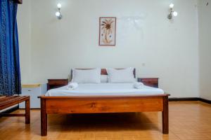 a bedroom with a wooden bed with white sheets at LOTUS HOTEL in Diego Suarez