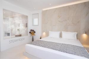 a white bedroom with a white bed and a wall at Cycladic Suites in Fira