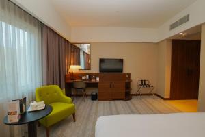 Habitación de hotel con cama, escritorio y TV. en The Grand Lux Hotel, en Doha