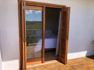 een glazen schuifdeur met een bed in een kamer bij Vale de cambara III in Cambará