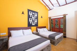 two beds in a room with yellow walls at Kuru Ganga Villa in Eratnagoda