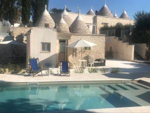 une maison avec piscine, deux chaises longues et un parasol dans l'établissement Pignarè, à Locorotondo