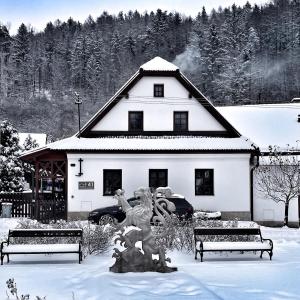 a white building with a statue in the snow at Chaloupka pod hradem in Svojanov