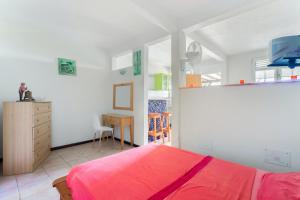 a bedroom with a red bed and a dresser at Appartement d'une chambre avec vue sur la mer jardin clos et wifi a Le Robert a 5 km de la plage in Le Robert